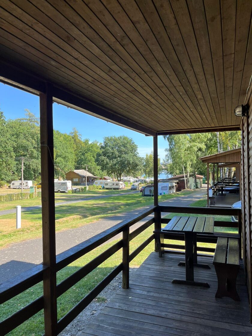 Výhled z dřevěné terasy chatky na areál kempu a přehradu Jesenice u Chebu – ukázka ubytování v přírodě